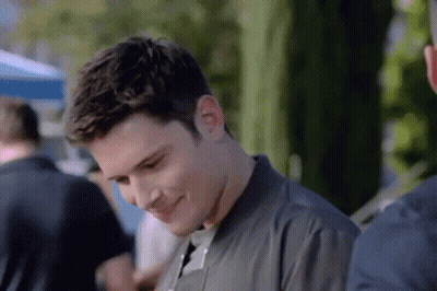 A Man In A Black Jacket Is Smiling While Standing Next To Another Man . GIF
