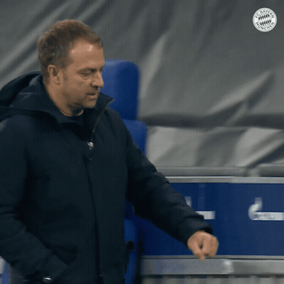 A Man In A Black Jacket Is Standing In Front Of A Blue Box That Says Fc Bayern Munich GIF
