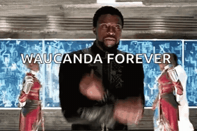 A Man In A Black Jacket Is Standing In Front Of A Chalkboard With The Words Waucunda Forever Written On It . GIF