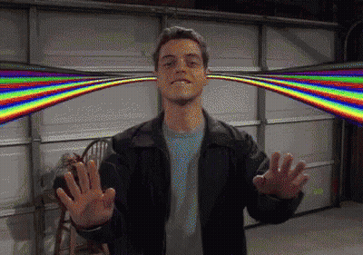 A Man In A Black Jacket Is Standing In Front Of A Garage Door With A Rainbow Behind Him GIF