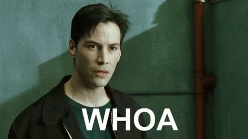 A Man In A Black Jacket Is Standing In Front Of A Green Wall With The Words `` Whoa '' Written On It . GIF