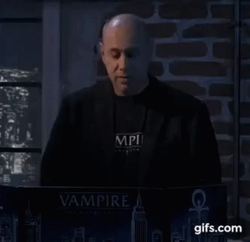 A Man In A Black Jacket Is Standing In Front Of A Laptop Computer . GIF