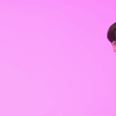 A Man In A Black Jacket Is Standing In Front Of A Pink Background . GIF