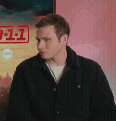 A Man In A Black Jacket Is Standing In Front Of A Poster That Says 911 GIF