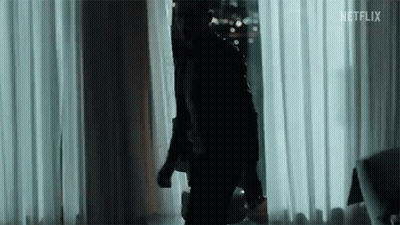A Man In A Black Jacket Is Standing In Front Of A Window In A Room . GIF