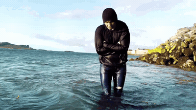 A Man In A Black Jacket Is Standing In The Water GIF