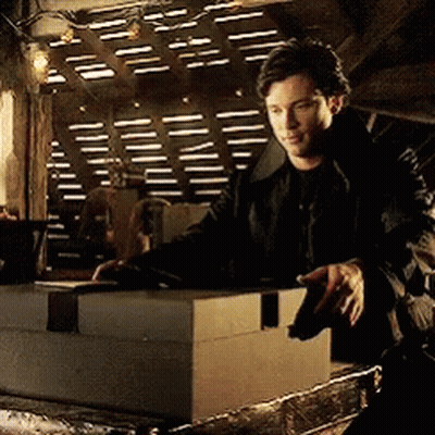 A Man In A Black Jacket Is Standing Next To A Large Box GIF