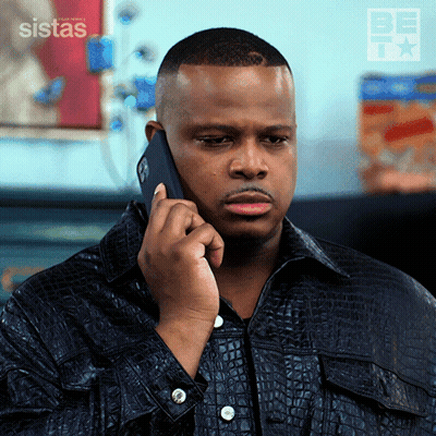 A Man In A Black Jacket Is Talking On A Cell Phone With A Sistas Logo Behind Him GIF