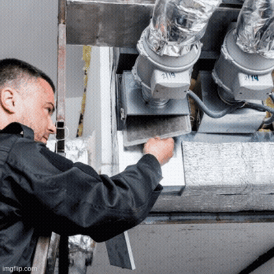 A Man In A Black Jacket Is Working On A Ventilation System With The Number 219 On It GIF