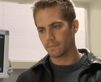A Man In A Black Jacket Looks At Something In Front Of A Monitor GIF