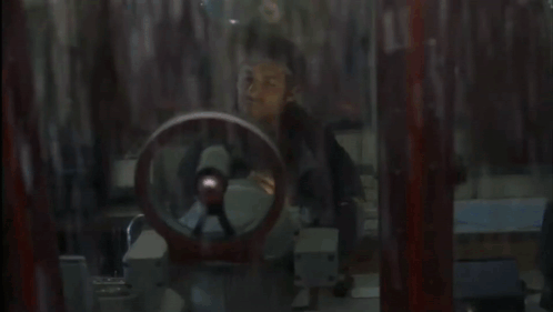 A Man In A Black Jacket Looks Out A Window GIF