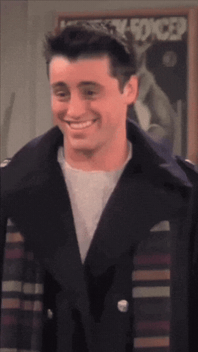 A Man In A Black Jacket Smiles In Front Of A Poster That Says Lucky Forced GIF