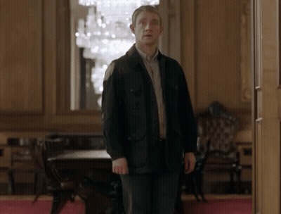 A Man In A Black Jacket Standing In A Room GIF