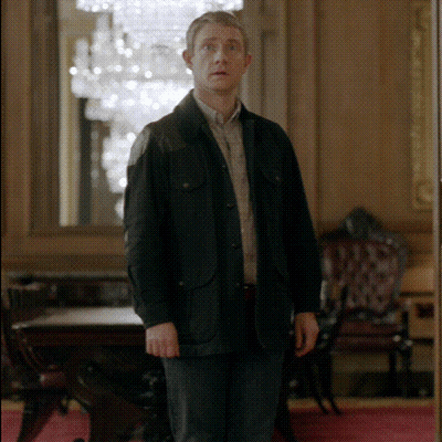 A Man In A Black Jacket Stands In A Room GIF