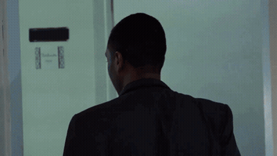 A Man In A Black Jacket Stands In A Room GIF