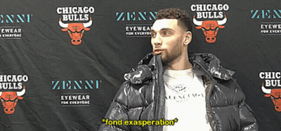 A Man In A Black Jacket Stands In Front Of A Chicago Bulls Backdrop GIF