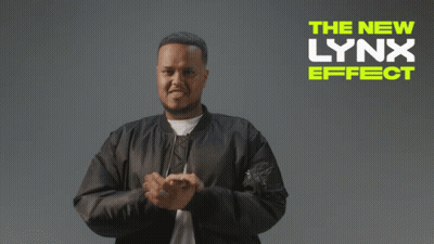 A Man In A Black Jacket Stands In Front Of A Lynx Effect Ad GIF