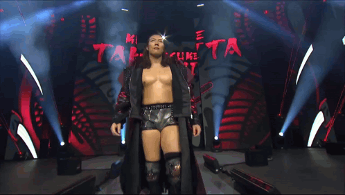 A Man In A Black Jacket Stands In Front Of A Sign That Says Grand Slam On It GIF