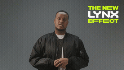 A Man In A Black Jacket Stands In Front Of A Sign That Says " The New Lynx Effect " GIF