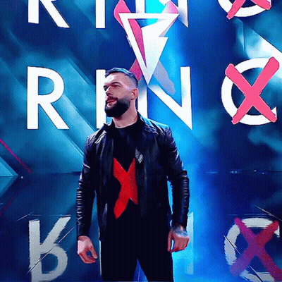 A Man In A Black Jacket Stands In Front Of A Wall With The Letters R And N On It GIF