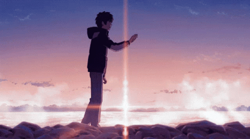 A Man In A Black Jacket Stands On A Rocky Shoreline GIF