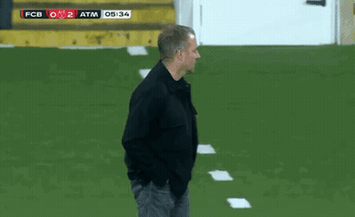 A Man In A Black Jacket Stands On A Soccer Field With The Scoreboard Showing Fcb 0 2 Atm GIF
