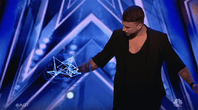 A Man In A Black Jacket Stands On A Stage With A Nbc Logo In The Corner GIF
