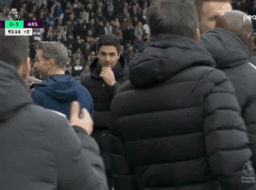 A Man In A Black Jacket Talks To Another Man In A Blue Jacket GIF