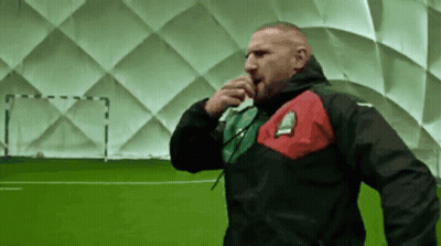 A Man In A Black Jacket With A Red And Green Stripe On The Sleeve GIF