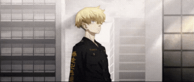 A Man In A Black Jacket With Chinese Writing On The Sleeves Stands In Front Of A Building . GIF