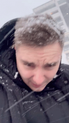 A Man In A Black Jacket With Snow On His Hair GIF