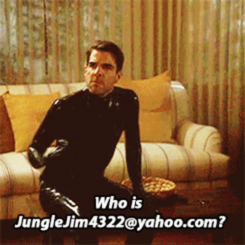 A Man In A Black Latex Suit Is Sitting On A Couch And Asking Who Is Jungle Jim4322@yahoo.com GIF