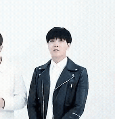 A Man In A Black Leather Jacket And White Shirt Is Standing Next To Another Man In A White Shirt . GIF
