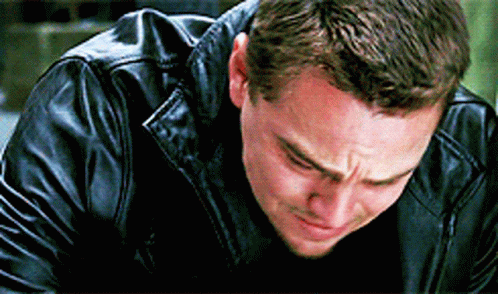 A Man In A Black Leather Jacket Is Crying While Looking Down . GIF