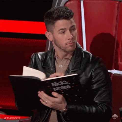 A Man In A Black Leather Jacket Is Reading A Book Called Nick 'S Notes GIF