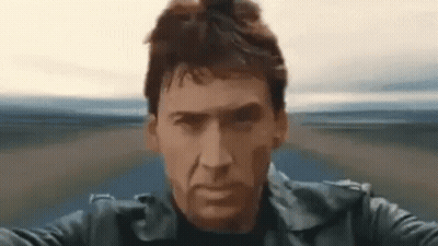 A Man In A Black Leather Jacket Is Riding A Motorcycle On A Road . GIF