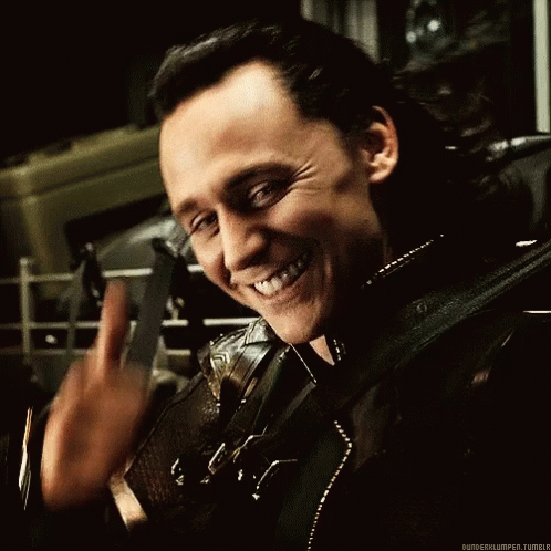 A Man In A Black Leather Jacket Is Smiling And Waving His Hand . GIF