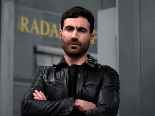 A Man In A Black Leather Jacket Stands In Front Of A Sign That Says Radar GIF