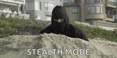 A Man In A Black Mask Is Hiding In The Sand . GIF