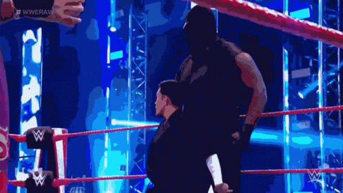 A Man In A Black Mask Is Standing In A Wrestling Ring With A W Logo On The Corner GIF