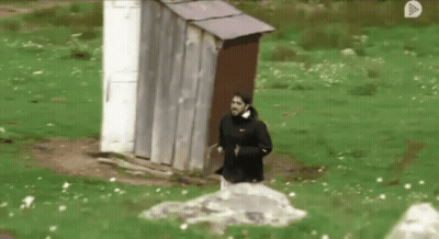 A Man In A Black Nike Jacket Is Running In Front Of An Outhouse GIF