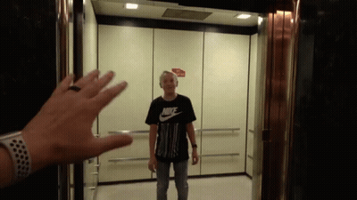 a man in a black nike shirt is standing in an elevator
