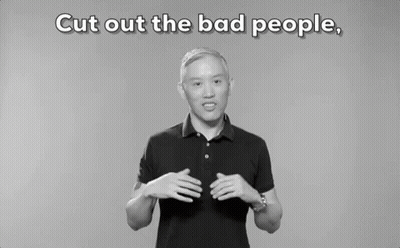 A Man In A Black Polo Shirt Is Standing In Front Of A Gray Background . GIF