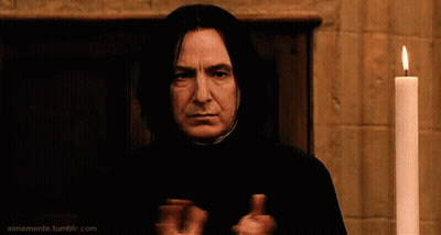 A Man In A Black Robe Is Standing In Front Of A Lit Candle And Giving A Thumbs Up . GIF