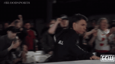 A Man In A Black Robe Stands In Front Of A Crowd With The Word Bloodsports On The Bottom Right GIF