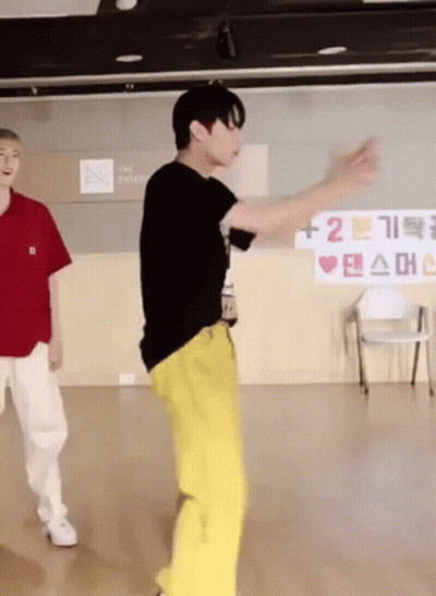 A Man In A Black Shirt And Yellow Pants Is Dancing In A Room GIF