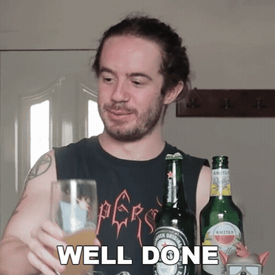 A Man In A Black Shirt Holds A Glass Of Beer In Front Of A Bottle Of Amstel Beer GIF