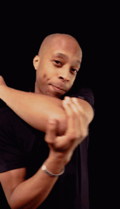 A Man In A Black Shirt Holds His Elbow Up In Front Of His Face GIF