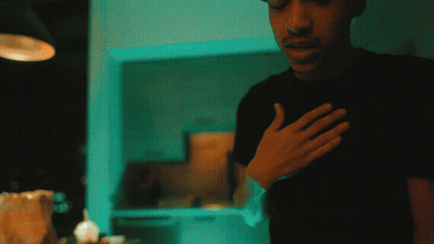 A Man In A Black Shirt Holds His Hand To His Heart GIF