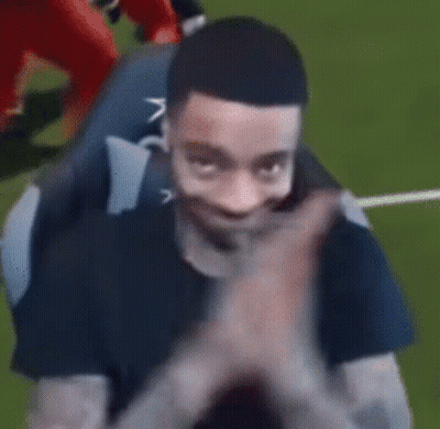 A Man In A Black Shirt Is Clapping His Hands While Sitting On A Couch . GIF